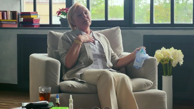 Portrait of senior pensioner sneezing and feeling sick isolating at home