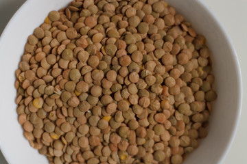 close-up of green lentil grits raw on a white plate on a light background. vegetarian food.