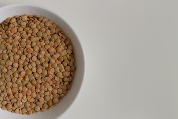 close-up of green lentil grits raw on a white plate on a light background. vegetarian food.
