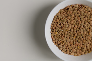 close-up of green lentil grits raw on a white plate on a light background. vegetarian food.
