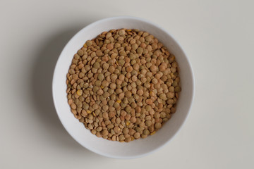 close-up of green lentil grits raw on a white plate on a light background. vegetarian food.