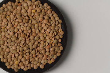 close-up of green lentil grits raw on a black plate on a light background. vegetarian food.