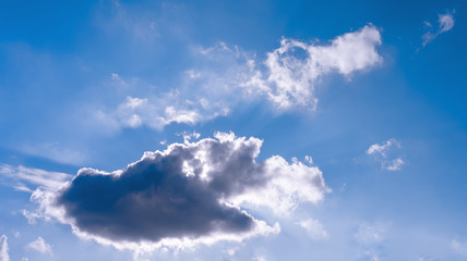 The bright sun breaks through the white cloud, the rays of the sun break through. Blue bright clear sky. Designer background.