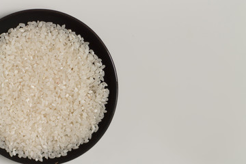 close-up of raw rice grits on a black plate on a light background. vegetarian food.