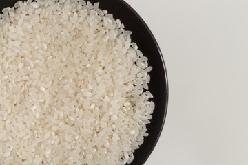 close-up of raw rice grits on a black plate on a light background. vegetarian food.