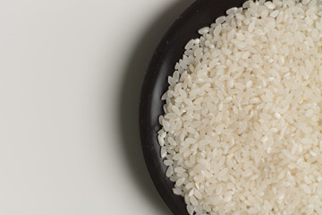 close-up of raw rice grits on a black plate on a light background. vegetarian food.