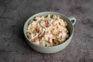 Bowl of traditional Russian salad called Olivie, Russian New Year or Christmas salad on wooden background. Salad from cooked vegetables. Potato salad.