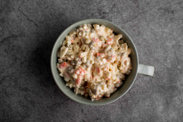 Bowl of traditional Russian salad called Olivie, Russian New Year or Christmas salad on wooden background. Salad from cooked vegetables. Potato salad.
