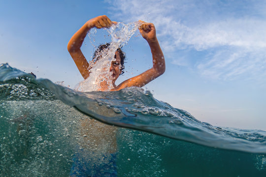 Children playing in the sea making splash of waters in the ocean in the summer. Shot in mid-water