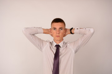 serious man in shirt with tie holds hands behind head portrait