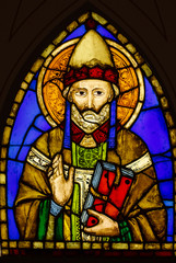Stained glass in church with priest image. Man with raised hand and book. Vintage image, colorful...