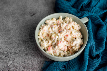Bowl of traditional Russian salad called Olivie, Russian New Year or Christmas salad on wooden background. Salad from cooked vegetables. Potato salad.