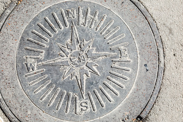 Obraz premium Sewer manhole with designation of cardinal points.