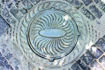 Iron street sewer manhole among the pavement stones.