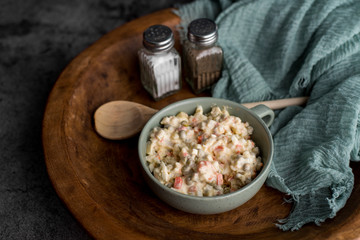Bowl of traditional Russian salad called Olivie, Russian New Year or Christmas salad on wooden background. Salad from cooked vegetables. Potato salad.