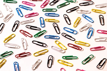 A lot of multi-colored colored paper clips on a white background. Background idea for business.