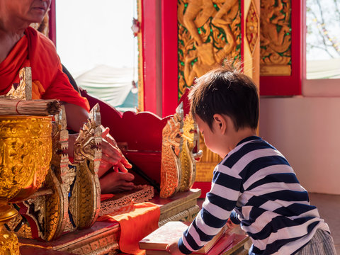 Buddhist little child boy give religious book tripitaka to monk in local temple in countryside. Family activity in holiday.
