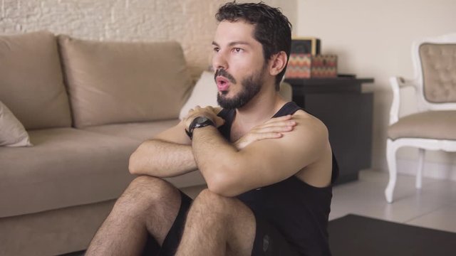 Healthy man doing sit-ups on the ground. Young athlete is practicing physical activity in the apartment living room
