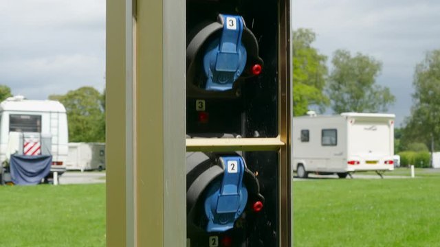 Vertical dolly shot of a multi-connection, electrical hook-up supply post, for mains power distribution to caravans and motorhomes, on a campsite in England, UK.