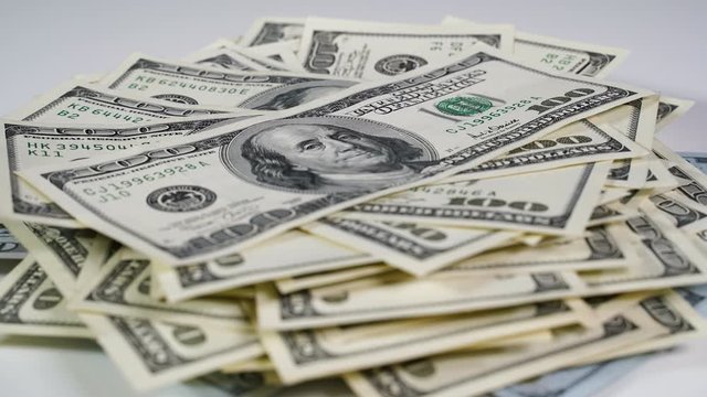 A pack of dollars increases in quantity on a white table. Stop motion
