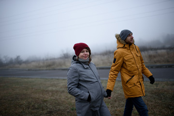 Fototapeta premium kochająca się w ciąży para spaceruje poza miastem późną jesienią.