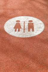 Fototapeta na wymiar Symbols for male and female toilets on a path with a red synthetic textured surface