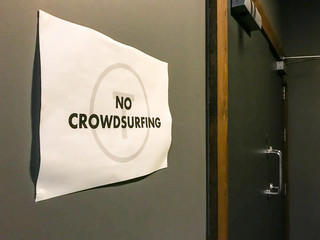 Sign on the wall of a night club stating "No crowd surfing"