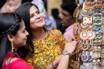 Two young girls are trying necklace and other jewelry in native accessories shop in India. Shopping...