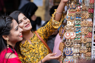 Two young girls are trying necklace and other jewelry in native accessories shop in India. Shopping for Indian festival or wedding .