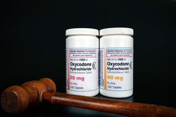 Oxycodone Hydrochloride prescription bottles isolated on black background with judge gavel infront....