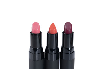 Three lipsticks in pink, orange and deep red against a white background