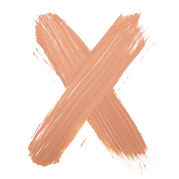 Letter X made with face skin concealer nude color.  Brush stroke make up base creamy texture isolated on white background.