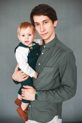 a one-year-old son sits in the arms of a young father