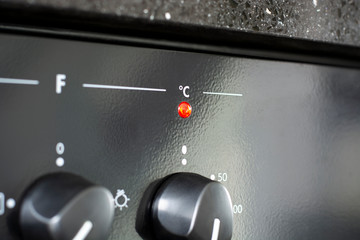 Celsius with red indicator light. Heating up the oven in kitchen
