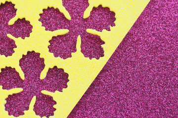 abstract background and texture of bright yellow shiny material with cut flowers on a purple shiny background..