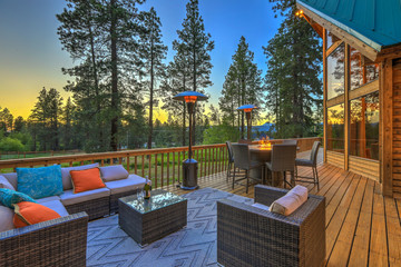 Luxury summer evening mountain home eteriors with cozy porch fire table and new furniture design.