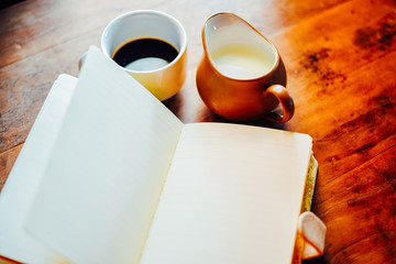 Top view Hot coffee with milk and open notebook  in white cup on the table in the morning