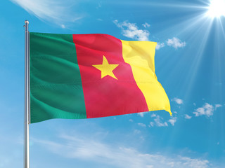 Cameroon national flag waving in the wind against deep blue sky. High quality fabric. International relations concept.