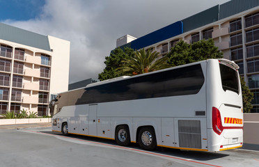 Naklejka premium Cape Town, South Africa. 2019. A white tourist bus at a hotel overlooked by accomodation rooms.