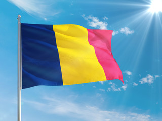 Chad national flag waving in the wind against deep blue sky. High quality fabric. International...