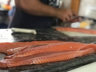 Peixe salmão cru, sendo limpado e cortado com fundo desfocado