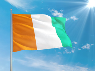 Cote D'Ivoire national flag waving in the wind against deep blue sky. High quality fabric....