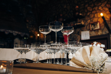 Empty wine glasses in form of pyramid on the festive table, there are napkins and flowers on the table