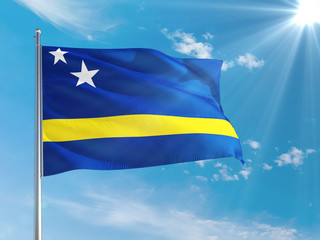 Curacao national flag waving in the wind against deep blue sky. High quality fabric. International relations concept.