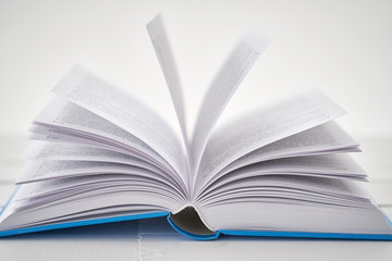 Opened blue book on white table. Low DOF
