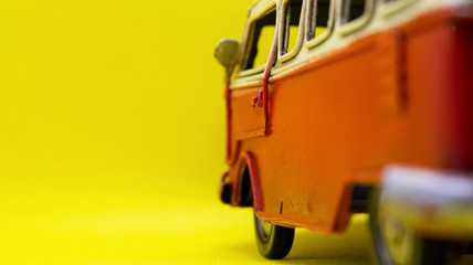 a red vintage caravan toy on yellow background
