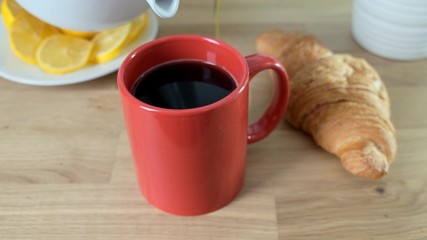 Pouring Milk In Coffee Glass cup on white kitchen table. Close up.