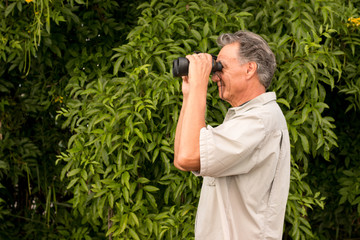 Senior Man outside enjoying nature looking through binoculars