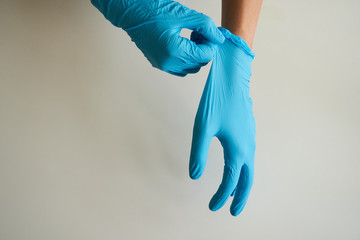 Woman hands remove a wearing blue disposable latex glove, taking off a rubber glove for...