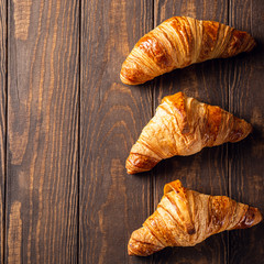 Food background with freshly baked sweet croissants on old wooden table. Breakfast or brunch concept with copy space, top view